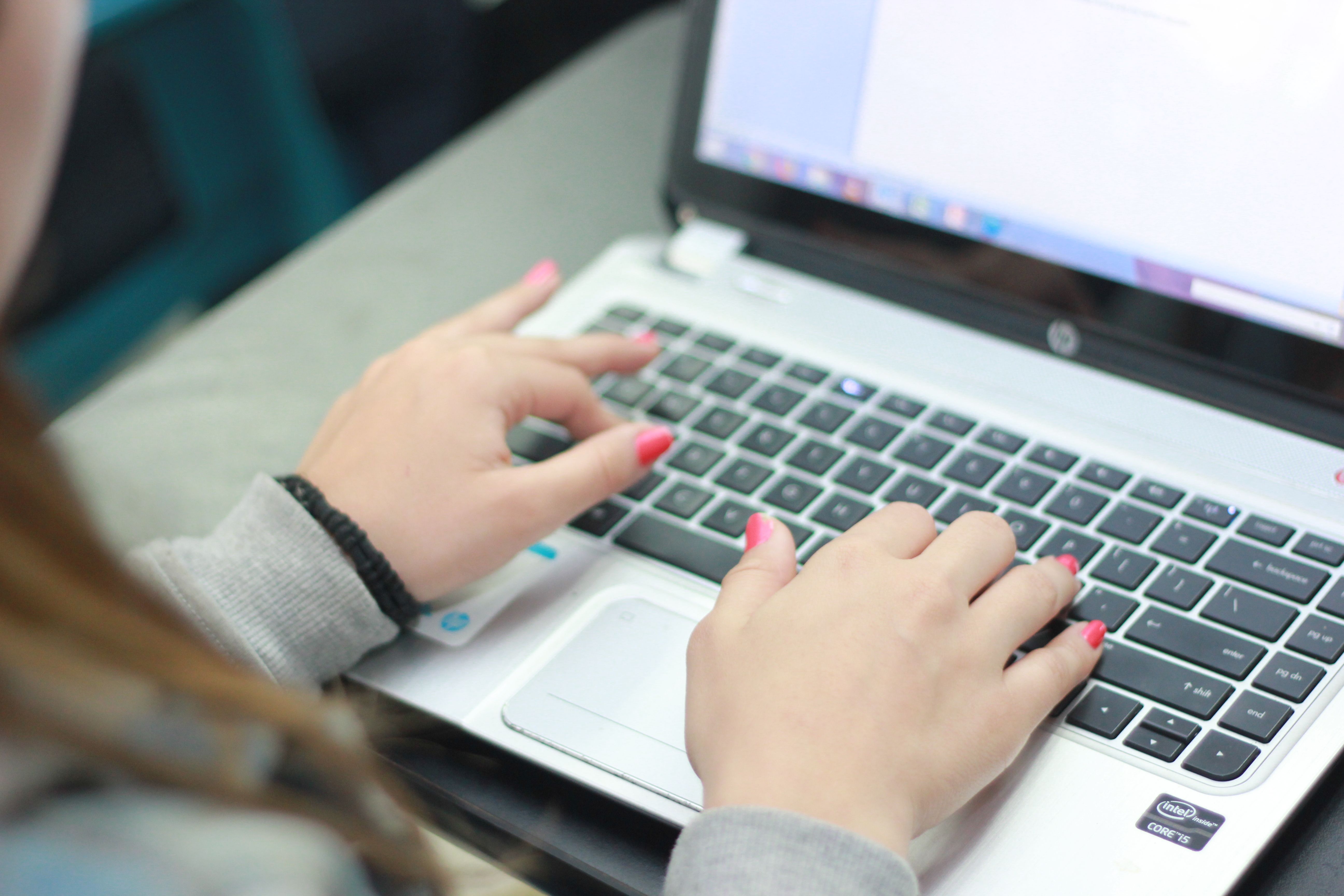 Close-up of human hands typing on a laptop keyboard, representing authentic human-written content